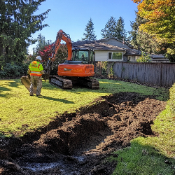 Worker and excavator digging trench in sunny backyard