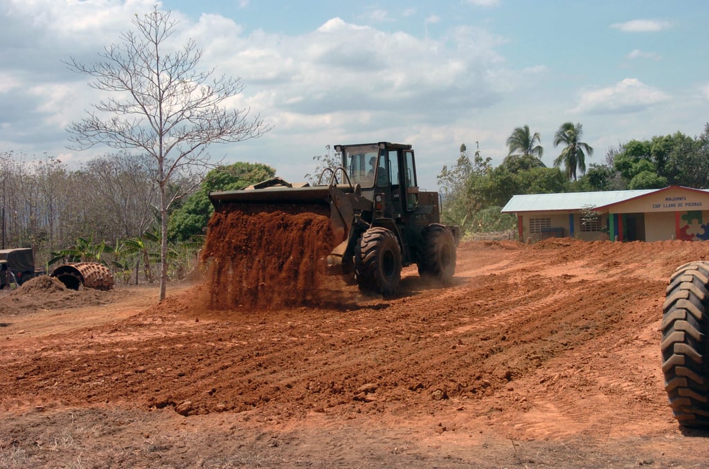 Bulldozer moving earth near rural schoolhouse