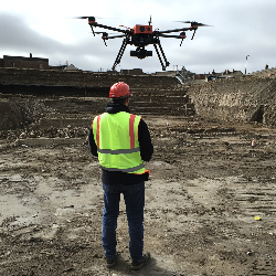 Worker monitoring drone at construction site