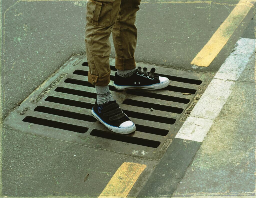 Person standing on street grate with sneakers