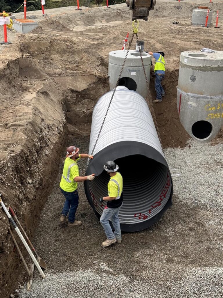 Workers installing large pipe at construction site