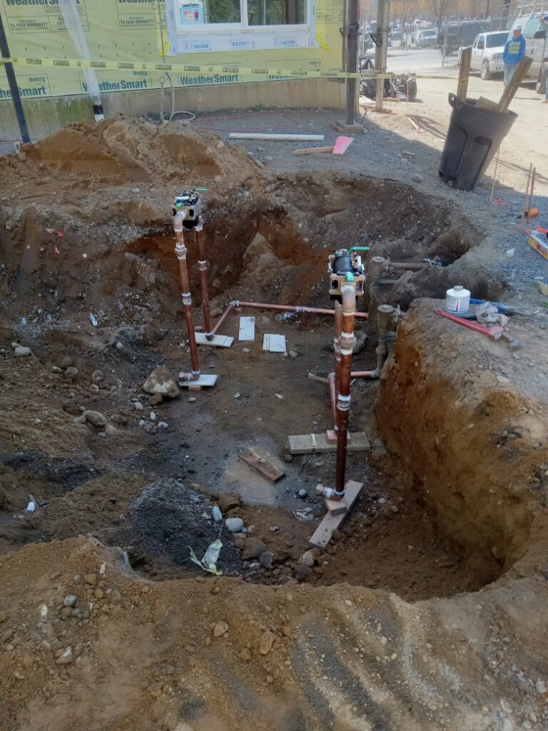 Excavation site with exposed pipes and construction debris