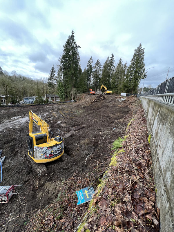 Excavators on muddy construction site near forest