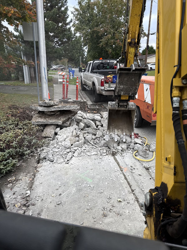 Excavator breaking pavement at construction site