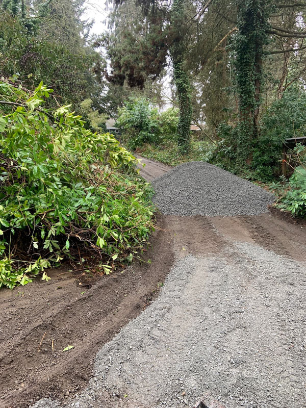 Gravel pile on forest driveway under cloudy sky